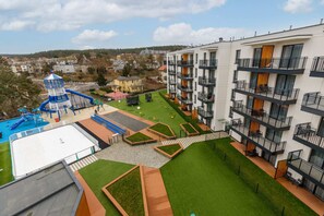 A view of a modern apartment complex with green courtyards and a vibrant community area.
