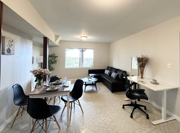 Living room with a sofa bed, a dining table, and a dedicated workspace