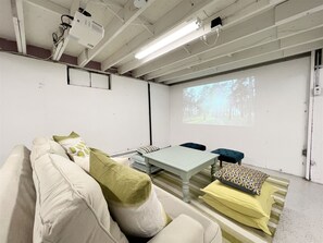 Basement theater room with projector, games, and cozy seating