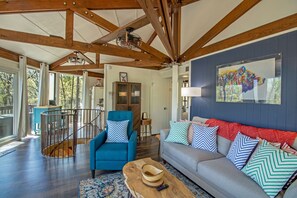 Living area with stone fireplace, lounge seating, television, and flooor-to-ceiling windows