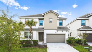 Modern family home with garage, palm trees, and bright curb appeal.
