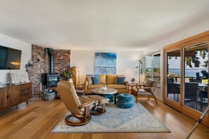 A wall of windows lights up the living room.  Quality leather furniture, a gas fireplace and a wall mounted smart TV.