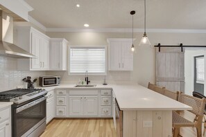 Chef’s Kitchen with Island Seating – Mallery Beach House - This stunning kitchen makes even vacation cooking feel fun—with quartz counters, a gas stove, stainless appliances, and room for everyone to gather around the island.