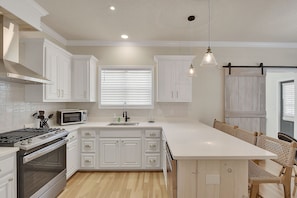 Chef’s Kitchen with Island Seating – Mallery Beach House - This stunning kitchen makes even vacation cooking feel fun—with quartz counters, a gas stove, stainless appliances, and room for everyone to gather around the island.