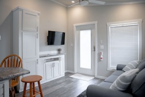 Cozy modern space: sofa, TV, kitchenette, and warm wood tones