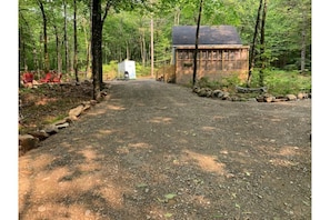 The front of the cabin with the fire pit, hammock, Privy and screened porch.