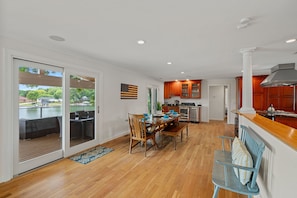 Doors to the covered deck with sectional, grill, table & chairs and loungers.