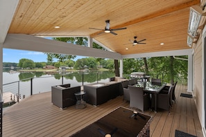 Covered deck with sectional, grill, table & chairs and loungers.