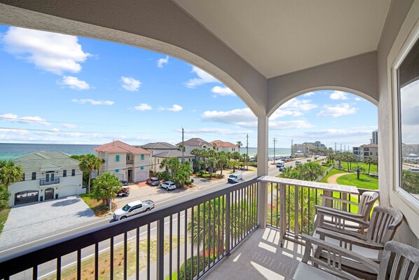 Sip coffee or enjoy evening drinks with this elevated view of palm trees, rooftops, and emerald waters