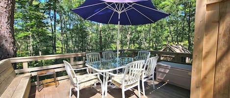 Wonderful deck with enclosed outdoor shower has a dining table and gas grill
