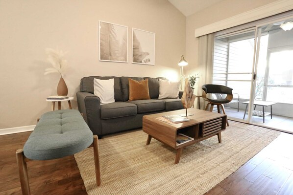 Relax in the cozy living room featuring modern decor, natural light, and direct access to the private patio.