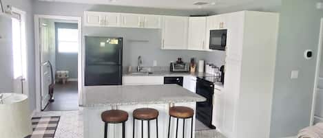 Open kitchen concept with all new cabinets, island, glass top stove.