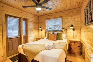 The primary bedroom has a queen size bed and a door to the deck with hot tub.