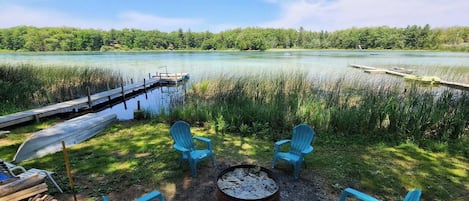 Fire pit with chairs right next to the lake.