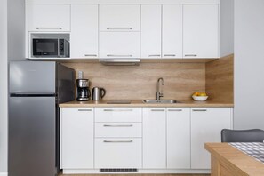 A white kitchen with a wooden countertop, fully equipped with modern appliances.
