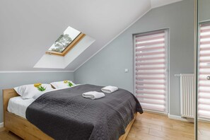 An attic bedroom with a bed and skylight window, offering plenty of natural light.
