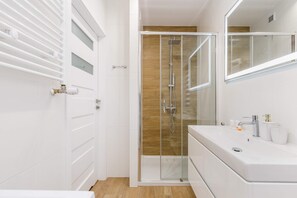 A bathroom with a shower, bright tiles, and a large mirror.

