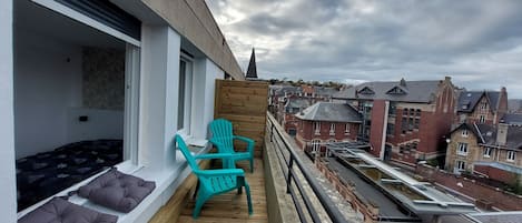 Un grand balcon avec vue sur les toits, quartier calme