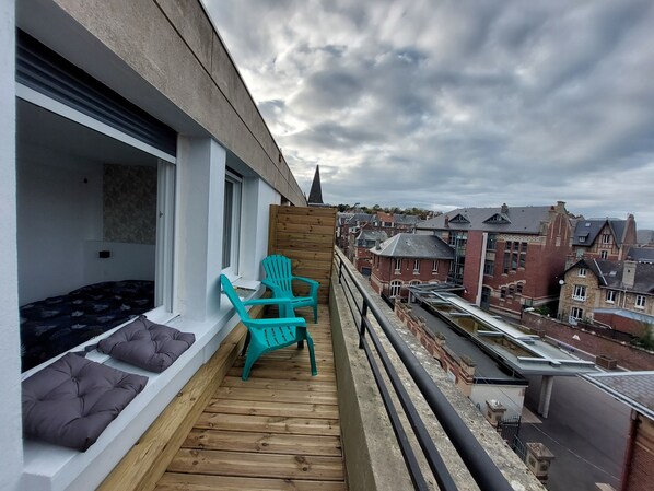 Un grand balcon avec vue sur les toits, quartier calme