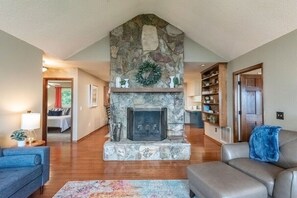 Main floor living room with wood burning fireplace. You can see the doorways to two of the three king bedrooms located off of the living room.