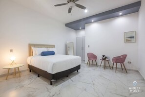 A plush queen bed and a nightstand with a lamp for reading