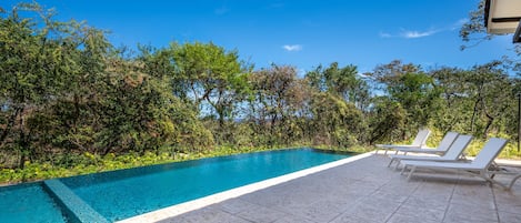 Spacious shared community pool surrounded by tropical greenery!