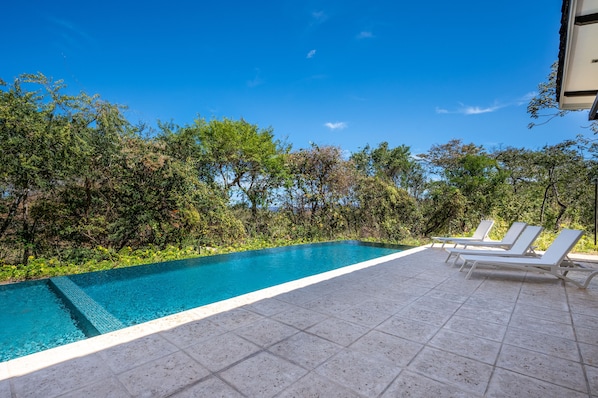Spacious shared community pool surrounded by tropical greenery!