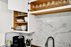 Kitchen equipped with wine glasses, plates, bowls, including plastic ware