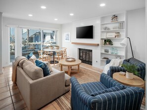 This warm, cozy living space offers direct access to an outdoor lounge area, complete with comfortable lounge amenities.