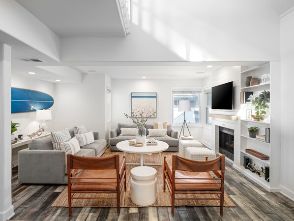 This freshly decorated living room boasts contemporary seating, designer furniture, a classic fireplace, and a smart TV, creating a cozy and stylish space.