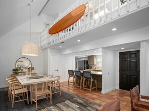 This open living room seamlessly integrates a formal dining area and a kitchen bar with ample seating, creating the perfect space for both casual and formal dining experiences.