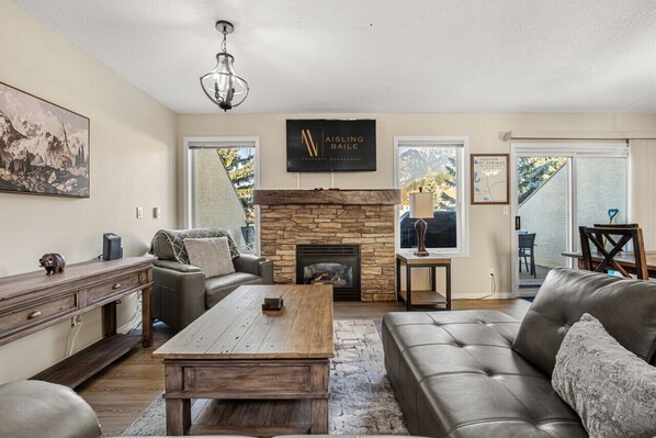 Living room on the main floor with a gas fireplace, Smart TV with cable, cozy seating and mountain views.