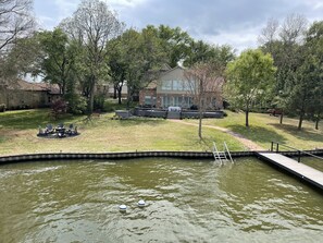 View from top of dock looking at house. Notice firepit on left and hot tub.