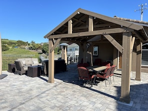 Outdoor dining and entertainment area in front of home overlooking the hillside. Gazebo covers dining table