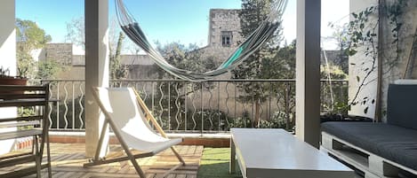 Terrasse / balcon ensoleillée et arborée avec mobilier jardin, table et hamac
