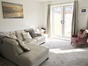 Spacious corner sofa with French doors to the patio and garden