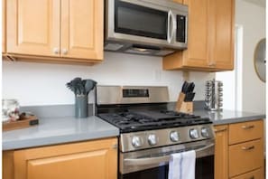 The kitchen is fully stocked with pots/pans, utensils, appliances and plates