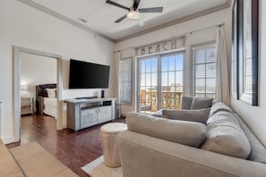 The living room has a large flat screen TV, a sleeper sofa and a private balcony