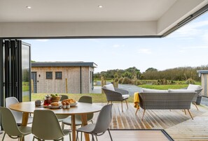 A single-storey modern eco lodge clad in cedar featuring floor to ceiling glass bi-folding doors.