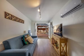Living room space facing patio courtyard with queen-size sofa bed and smart TV