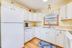 A pristine white kitchen featuring traditional appliances, blending timeless charm with modern functionality.