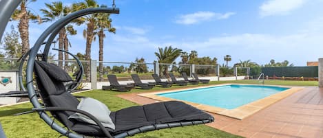 One of 2 comfortable swing chairs overlooking garden, pool and golf course