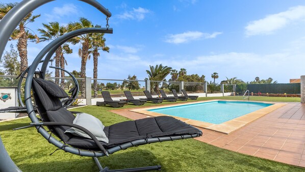 One of 2 comfortable swing chairs overlooking garden, pool and golf course