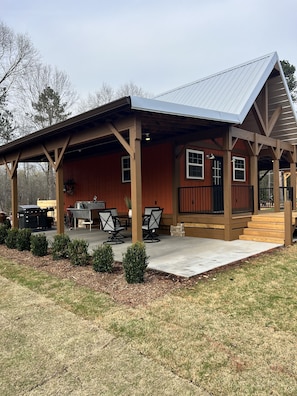 Complete outdoor kitchen with TV, grill, sink and comfortable dining set.
