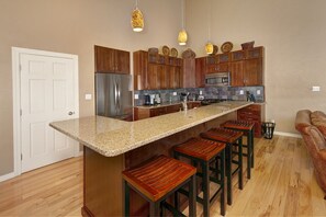 Main level full kitchen with stainless steel appliances and bar area.