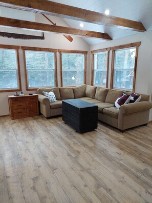 The living room has an undisrupted panoramic view of the forest.
