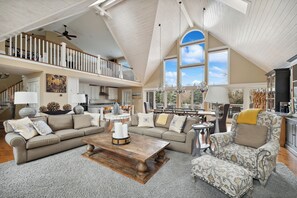 xperience the elegance of this large living room, featuring a magnificent vaulted ceiling and ample natural light. The Christmas candle brings a serene glow, perfect for celebrating the season with loved ones.