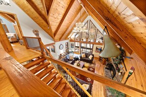 View of living room from the loft game room, sliding glass doors lead to deck