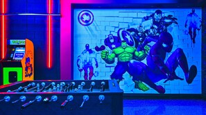Retro arcade room with foosball and Marvel mural for epic gaming nights.