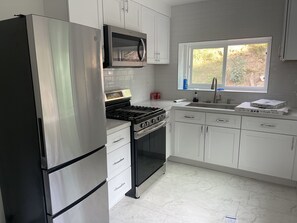 Kitchen with stove, microwave, fridge, coffee machine